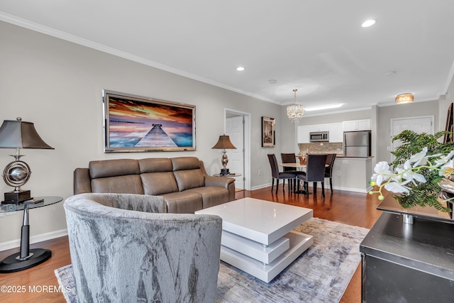 living room with an inviting chandelier, crown molding, and light hardwood / wood-style flooring