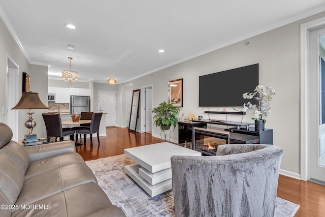 living room featuring crown molding, wood-type flooring, sink, and a notable chandelier