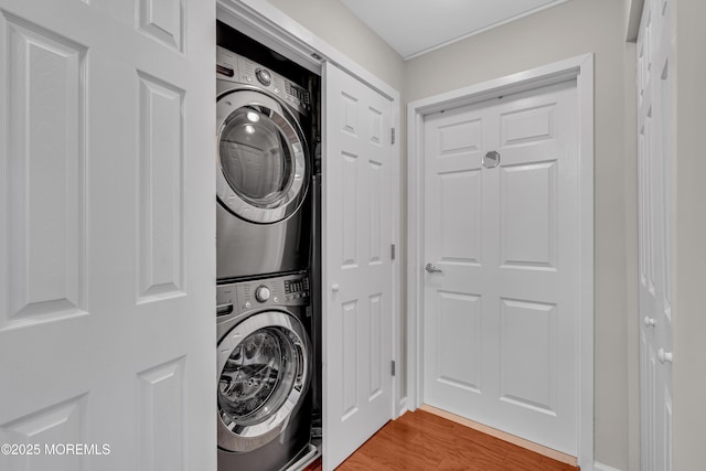 washroom featuring wood-type flooring and stacked washer and clothes dryer