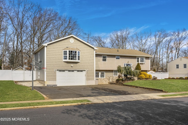 view of front of property featuring driveway, a front lawn, an attached garage, and fence