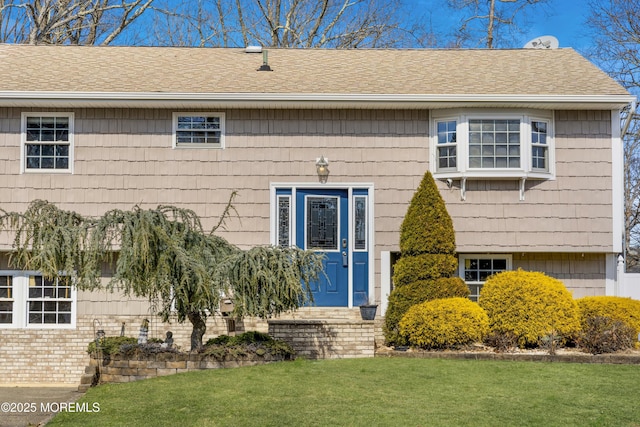 entrance to property featuring a shingled roof and a lawn