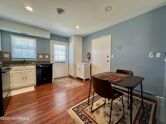 interior space with dark hardwood / wood-style flooring, black appliances, and white cabinets