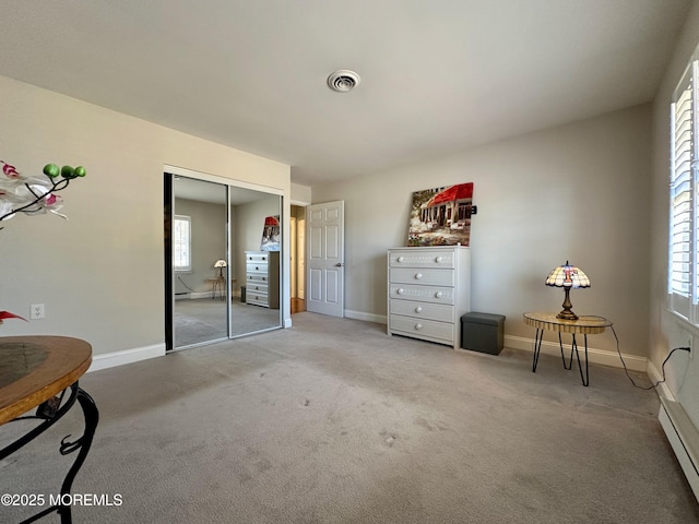 bedroom with a closet, baseboard heating, and carpet