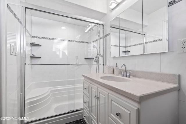 full bathroom with a stall shower, tile walls, vanity, and decorative backsplash