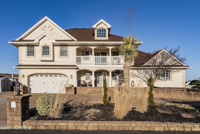 view of front of home featuring stucco siding, driveway, a porch, an attached garage, and a balcony