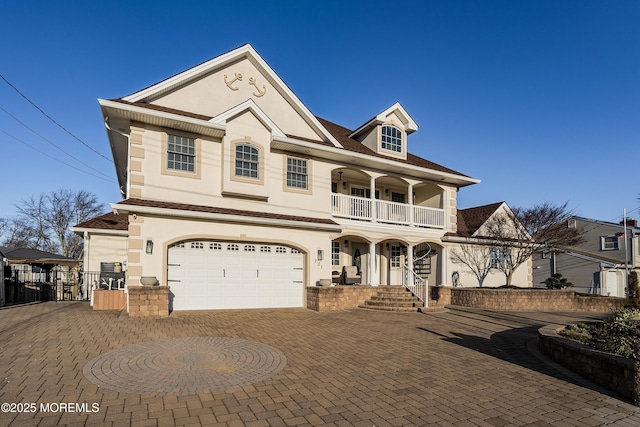 view of front of property featuring stucco siding, decorative driveway, a balcony, and a gate