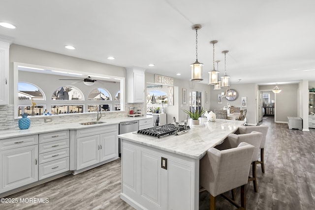 kitchen with backsplash, a kitchen island, a kitchen bar, white cabinetry, and a sink