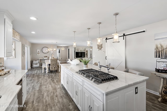 kitchen with dark wood-style floors, a barn door, appliances with stainless steel finishes, white cabinets, and light stone countertops