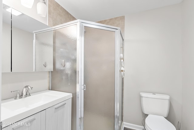 bathroom featuring toilet, a stall shower, and vanity