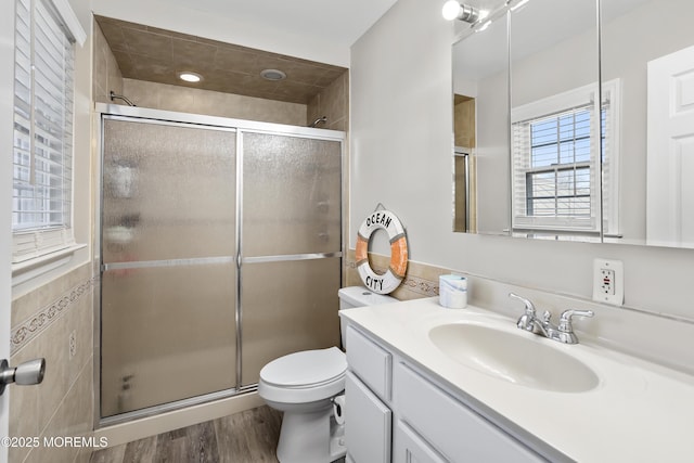 full bathroom with toilet, a stall shower, wood finished floors, tile walls, and vanity