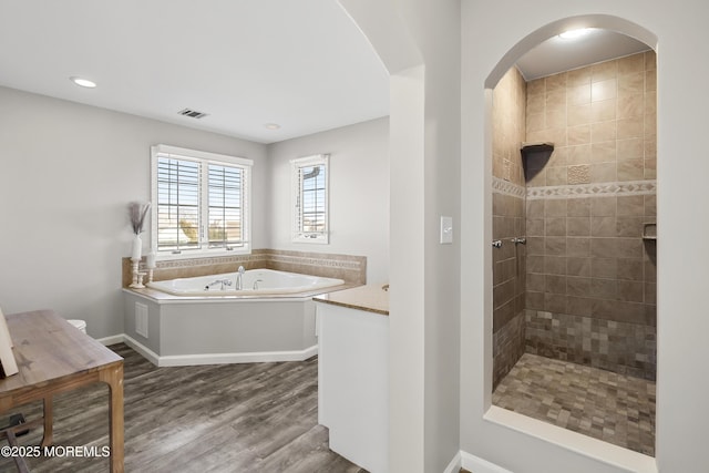 full bathroom featuring wood finished floors, visible vents, baseboards, a tile shower, and a garden tub