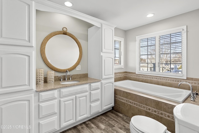 bathroom with vanity, wood finished floors, recessed lighting, a garden tub, and toilet