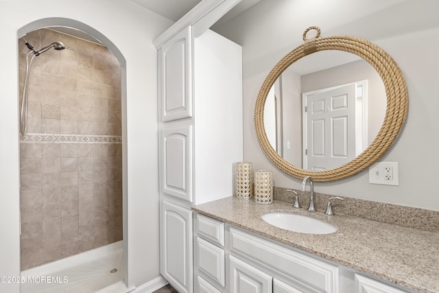 full bathroom featuring tiled shower and vanity