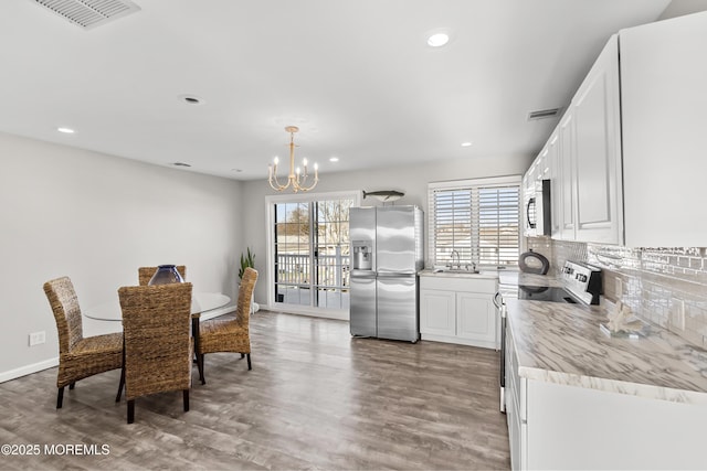 dining room with a notable chandelier, visible vents, recessed lighting, and wood finished floors