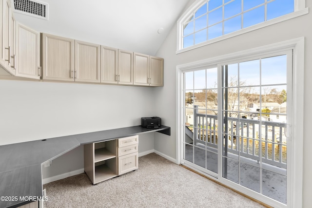 office featuring visible vents, high vaulted ceiling, baseboards, light colored carpet, and built in study area