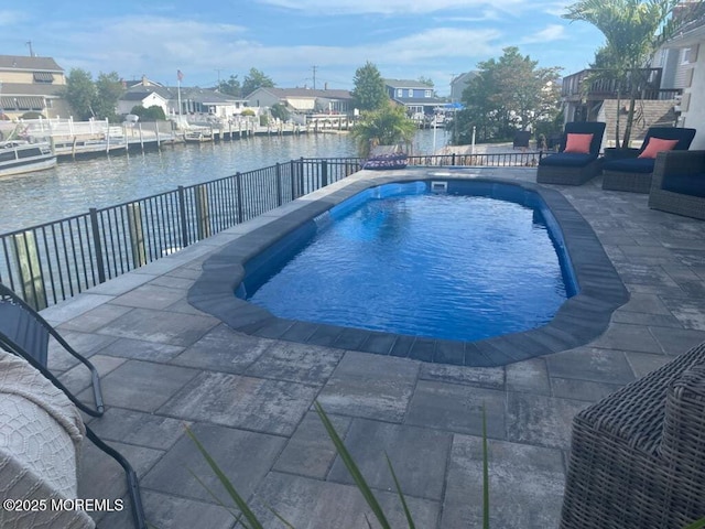 view of swimming pool with a fenced in pool, fence, a water view, a residential view, and a patio area