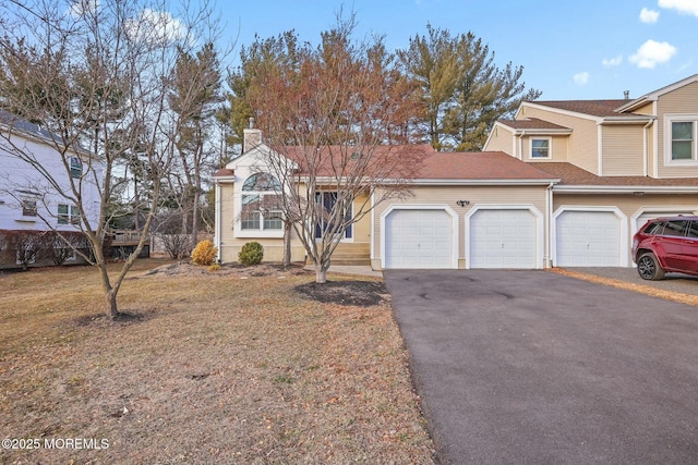 view of front of house with a garage, a chimney, a front lawn, and aphalt driveway