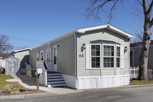 view of front of house featuring an outbuilding, fence, and a storage unit