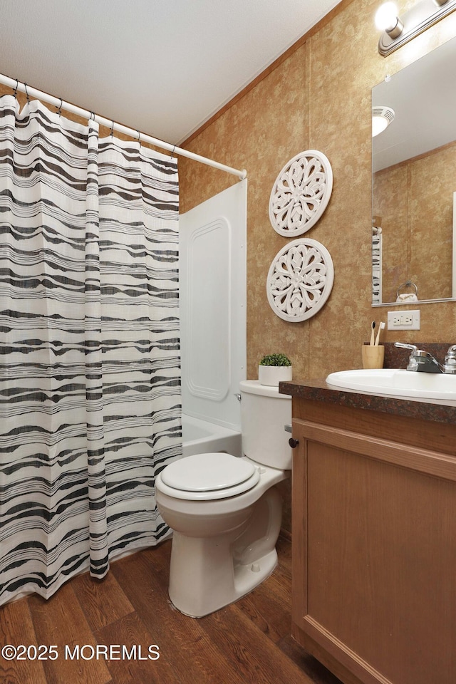 bathroom with toilet, wood finished floors, vanity, ornamental molding, and shower / bath combo