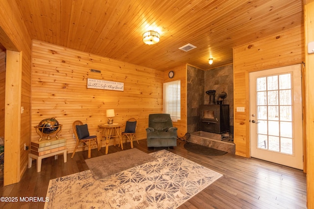 sitting room featuring wood-type flooring, a healthy amount of sunlight, and a wood stove
