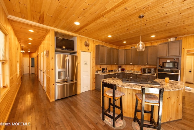 kitchen featuring appliances with stainless steel finishes, a center island, dark hardwood / wood-style floors, and decorative light fixtures