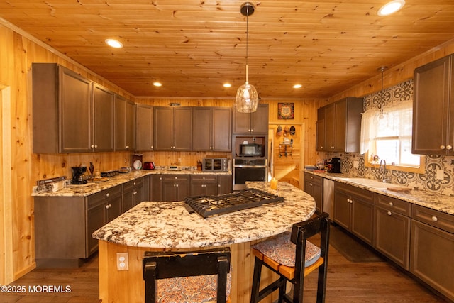 kitchen with hanging light fixtures, sink, light stone countertops, and a center island