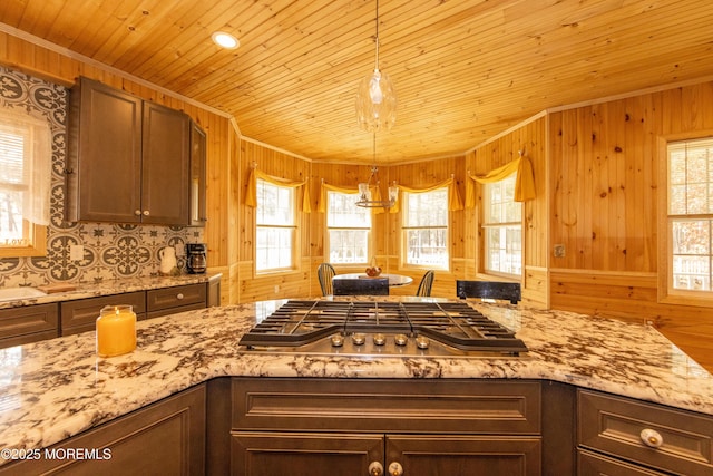 kitchen with stainless steel gas cooktop, wood walls, tasteful backsplash, dark brown cabinets, and wooden ceiling