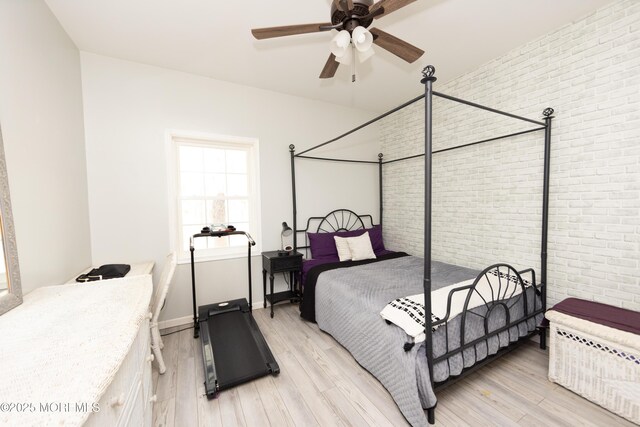 bedroom with light hardwood / wood-style flooring and brick wall