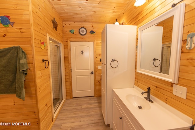 bathroom featuring wood walls, wood ceiling, wood-type flooring, vanity, and a shower with door