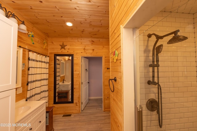 interior space featuring sink, light hardwood / wood-style floors, wooden ceiling, and wood walls