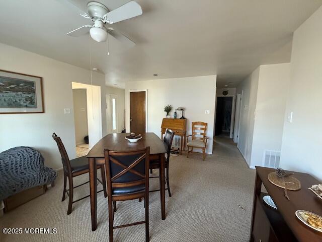 dining area featuring light colored carpet and ceiling fan