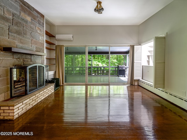 unfurnished living room featuring wood-type flooring, a wall mounted AC, a fireplace, and a baseboard heating unit