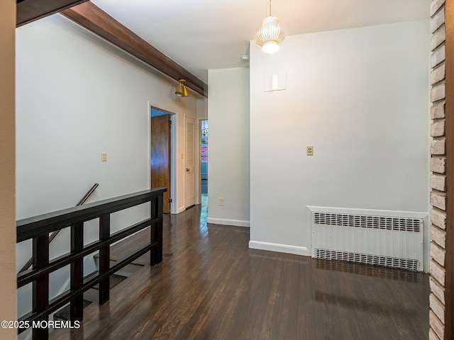 spare room with radiator, dark wood-style flooring, baseboards, and beamed ceiling
