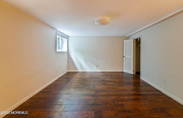 spare room featuring dark wood finished floors and baseboards