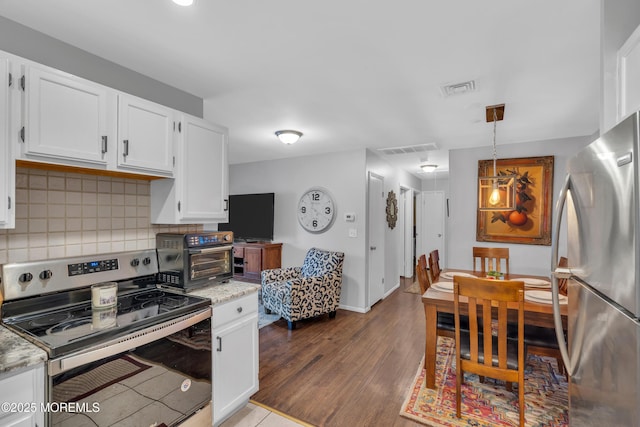 kitchen featuring appliances with stainless steel finishes, white cabinetry, pendant lighting, and light stone countertops