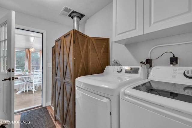 laundry area featuring independent washer and dryer, cabinets, and hardwood / wood-style floors