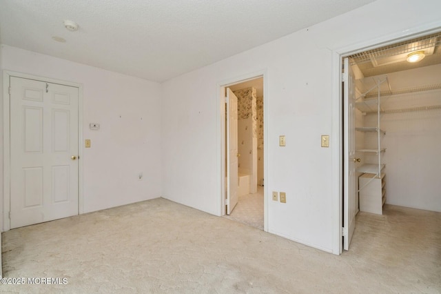 unfurnished bedroom featuring light carpet, connected bathroom, a walk in closet, and a closet