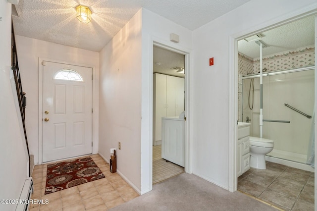 entryway with washer / dryer, baseboards, a textured ceiling, and baseboard heating