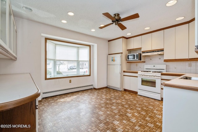 kitchen with white appliances, white cabinets, baseboard heating, light countertops, and under cabinet range hood