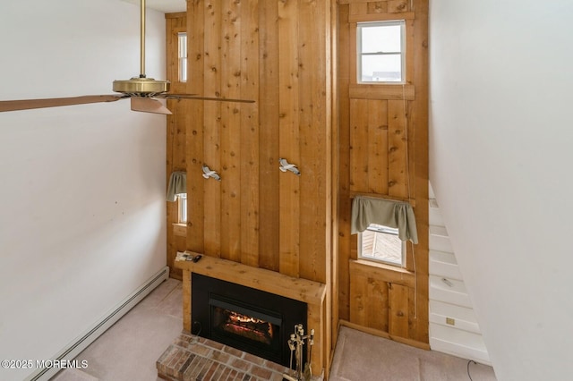 interior space with a baseboard radiator, a glass covered fireplace, and wooden walls