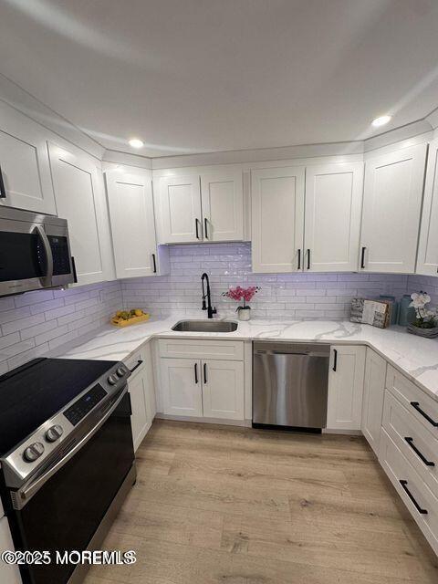 kitchen featuring white cabinetry, sink, stainless steel appliances, and light hardwood / wood-style floors