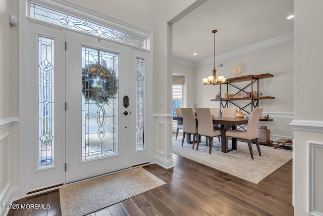 entrance foyer featuring a notable chandelier, a healthy amount of sunlight, dark wood-style floors, and crown molding