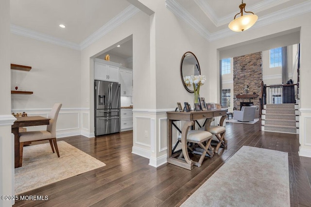 foyer with crown molding, wainscoting, dark wood-style flooring, and a decorative wall