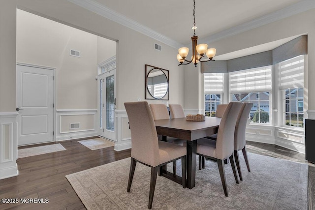 dining area featuring visible vents, ornamental molding, dark wood finished floors, an inviting chandelier, and a decorative wall