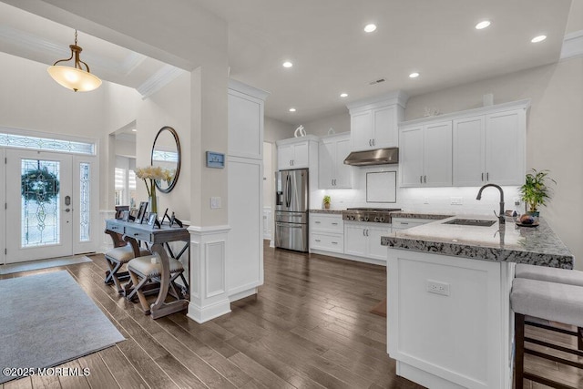 kitchen featuring under cabinet range hood, a sink, white cabinetry, appliances with stainless steel finishes, and a peninsula