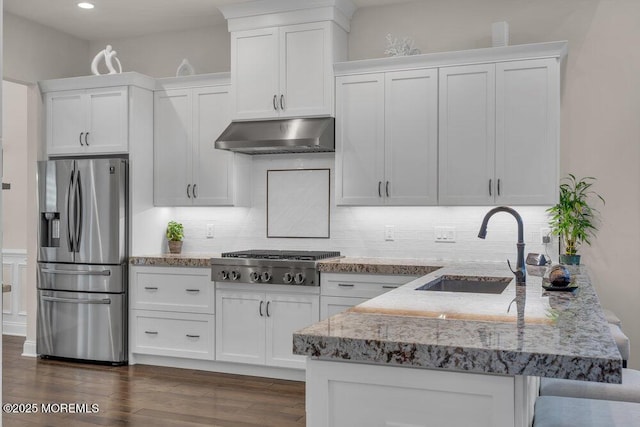 kitchen featuring under cabinet range hood, a sink, stainless steel appliances, a peninsula, and white cabinets