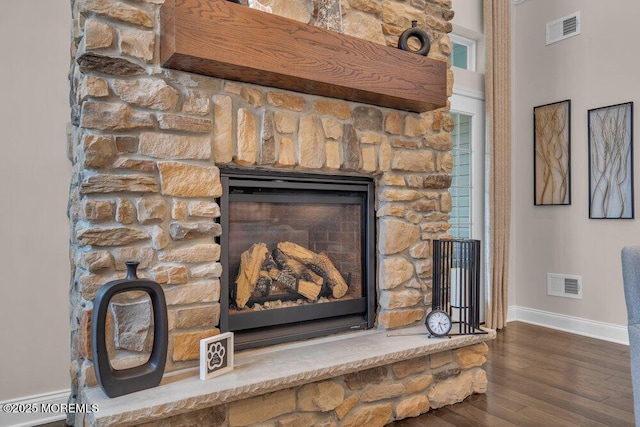 details featuring a fireplace, wood finished floors, visible vents, and baseboards