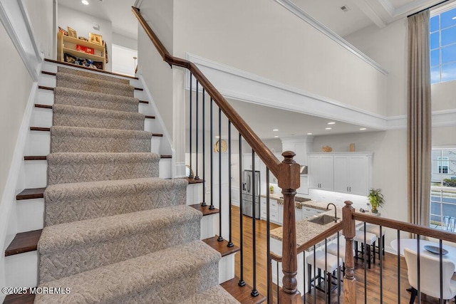 staircase with recessed lighting, a high ceiling, and wood finished floors