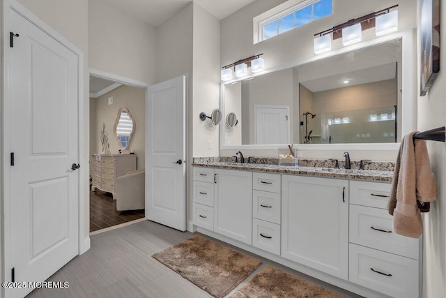 full bath with double vanity, a shower stall, wood finished floors, and a sink