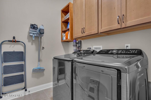 laundry room with tile patterned flooring, cabinet space, baseboards, and washer and clothes dryer